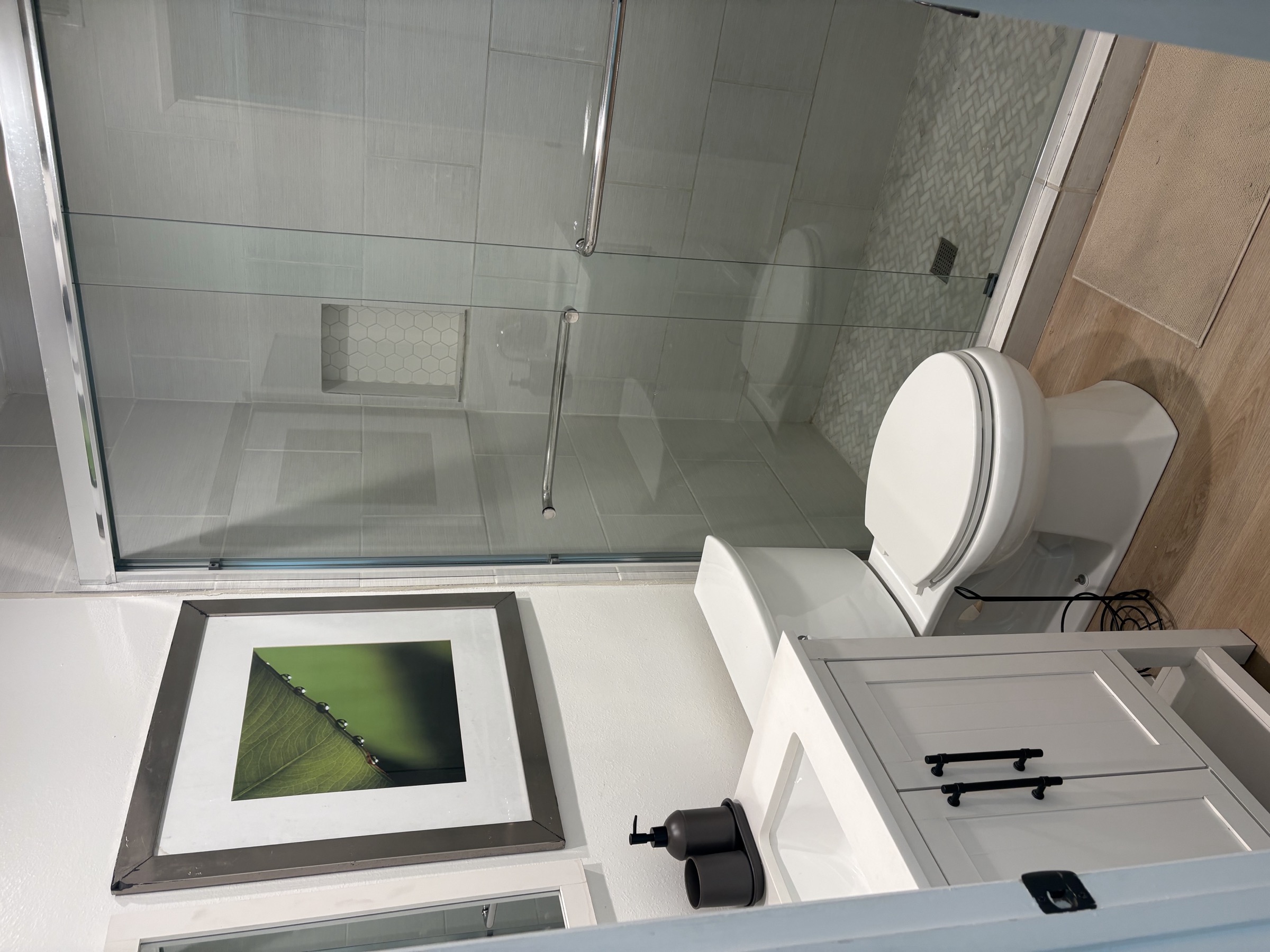 A bathroom with a glass-enclosed shower and grab bars