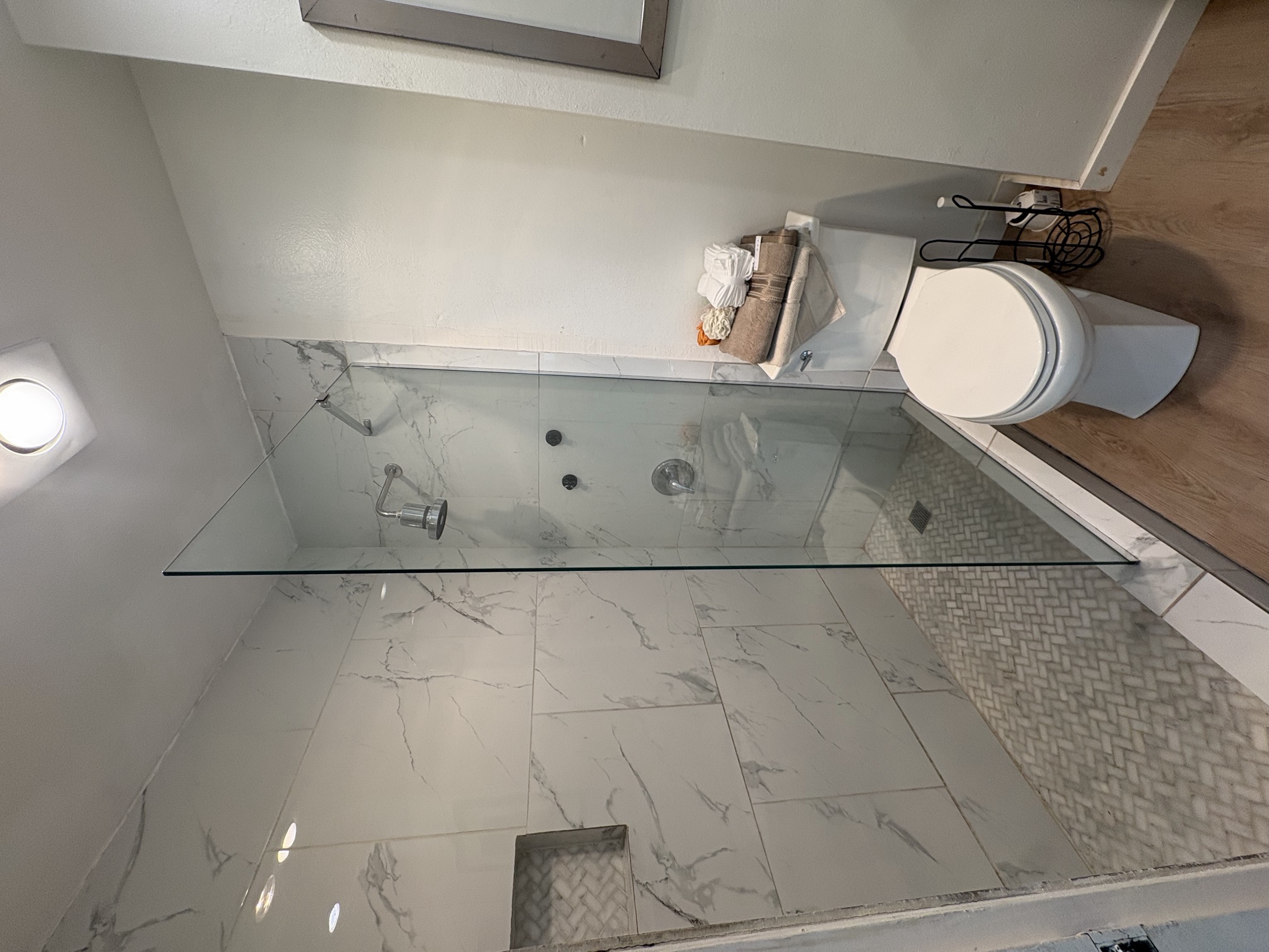 A bathroom with a marble-tiled walk-in shower